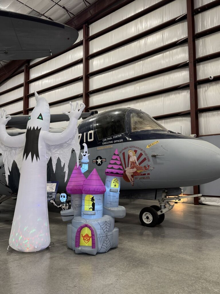 A giant inflatable ghost and an inflatable haunted castle beside a Navy S-3 Viking aircraft